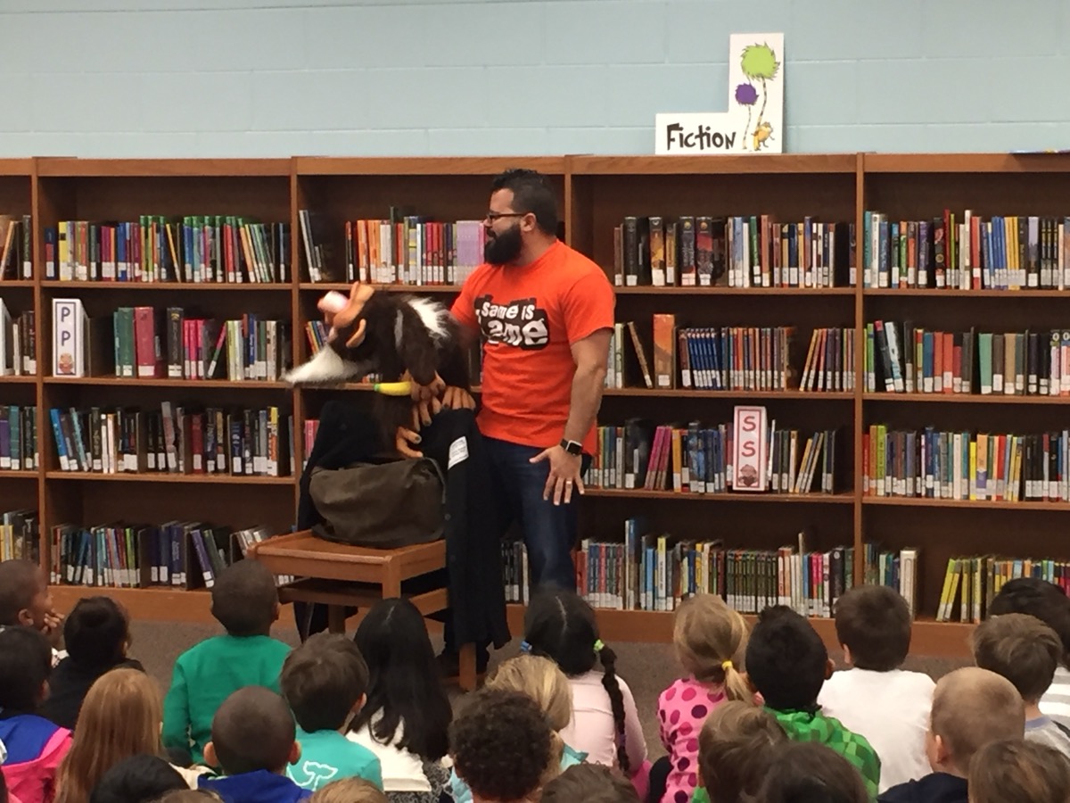 Jimmy Vee performing with a figure to children seated on a library floor
